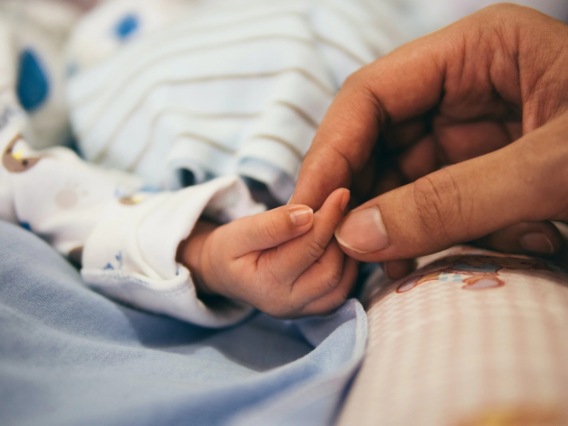 Mother and baby holding hands.